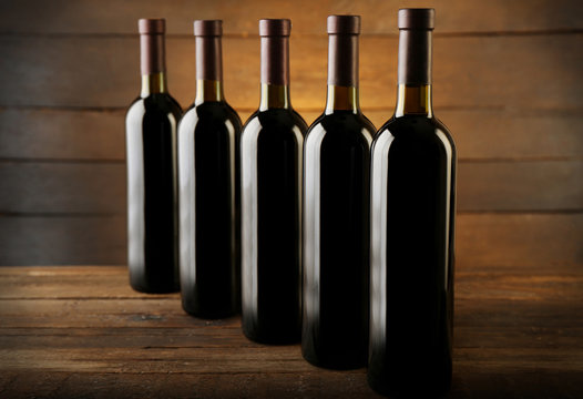 Wine bottles in a row on the table against wooden background