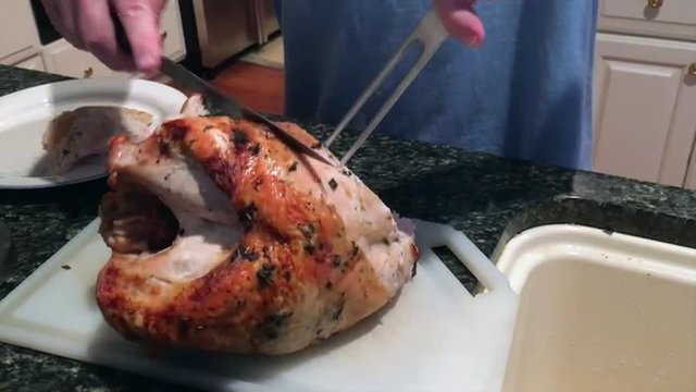 Man carving a turkey in a kitchen