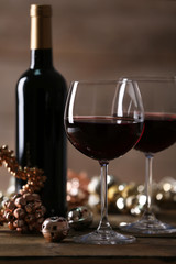 Red wine and Christmas ornaments on wooden table on wooden background