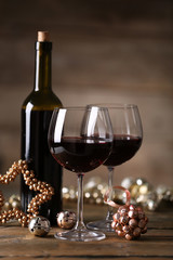Red wine and Christmas ornaments on wooden table on wooden background