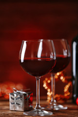 Red wine and Christmas ornaments on wooden table on wooden background