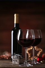 Red wine and Christmas ornaments on wooden table on wooden background