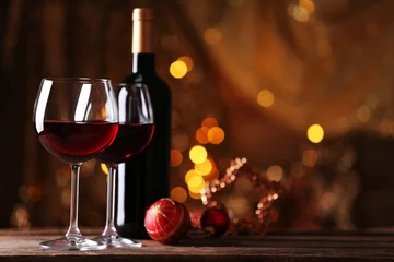 Gordijnen Rode wijn en kerstversieringen op houten tafel op gouden achtergrond © Africa Studio