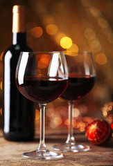 Red wine and Christmas ornaments on wooden table on golden background