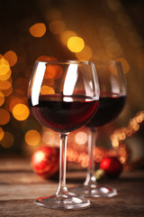 Red wine and Christmas ornaments on wooden table on golden background