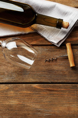 Bottle of wine with glass and corkscrew on wooden background