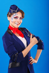 Stewardess with face art shows thumb up.