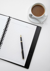 Notebook with a pen and a cup of coffee