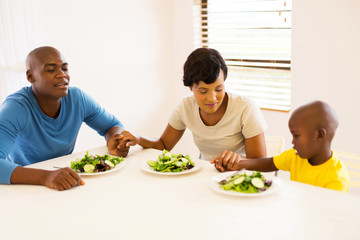 young african family praying before having meal