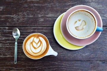 cup of latte art coffee and empty cup of coffee on wooden background