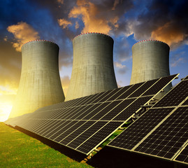 Solar energy panels and nuclear power plant at sunset.
