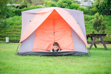 Little boy living inside the tent in the park