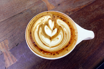cup of latte art coffee on wooden background