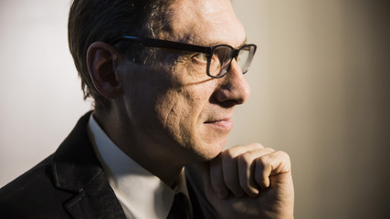 close portrait of an adult man in profile thinking in a dark room