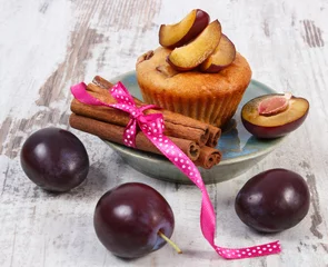 Foto op Plexiglas Fresh baked muffins with plums and cinnamon sticks on old wooden background, delicious dessert © ratmaner