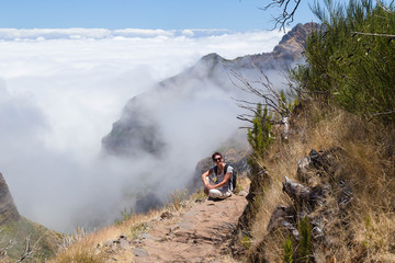 The girl sits has a rest on a tourist track in the mountains of