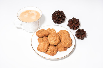 White cup of espresso coffee, cookies and fir cones on white background 