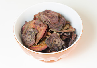 Thin round beetroot chips baked in the oven with oregano and salt and ripe beet roots in a bowl isolated on white background.Healthy,vegetarian,vegan,crispy snack appetiser for diet and clean eating 