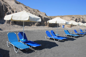 Chaise lounges on black beach of Santorini island, Greece