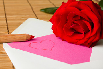 Love letter next to a red rose.