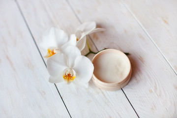 face cream with white orchid on  wooden table.