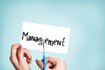 Woman hands cutting card with the word management