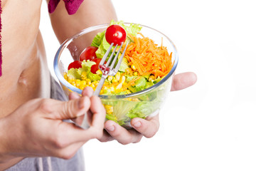 Close-up of a fitness man holding a bowl of salad, isolated on w