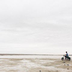 hipster man silhouette  drive on motocycle on the sea beach