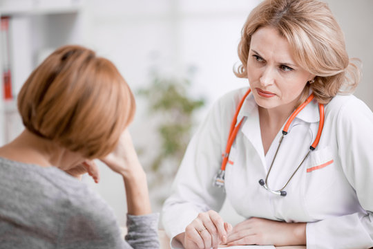 Serious doctor or physician looking at upset patient
