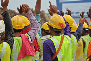 Group of construction workers raise their hand and assemble at the open space  - obrazy, fototapety, plakaty