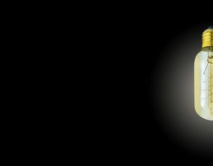 glowing amber vintage edison light bulb isolated on black background