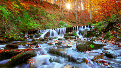 Fototapeta na wymiar Beautiful waterfall in forest at sunset