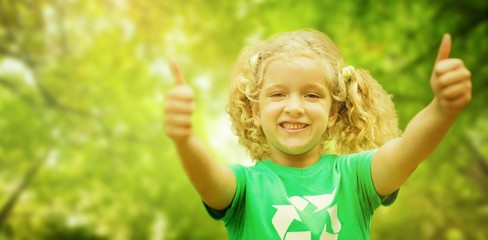 Composite image of happy little girl in green with thumbs up 