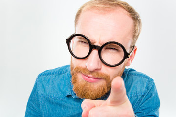 Suspicious bearded man in funny round glasses pointing on you