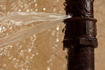 Rusty burst pipe squirting water at high pressure - obrazy, fototapety, plakaty