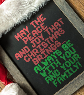 May the Peace and Joy that Brings... Always be With You and Your Family written on blackboard with santa hat