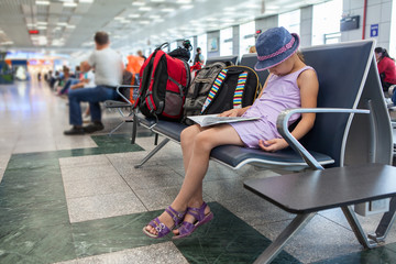 Tired Caucasian girl sleeping in the waiting room at the airport terminal, sitting on a chair.