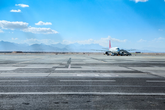 Airport runway and airfield with airliner standing under maintenance, copy space