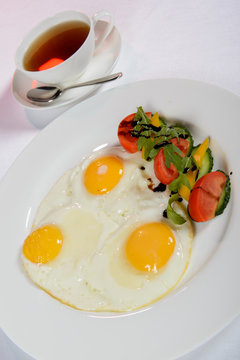 Fried eggs for breakfast with fresh tomatoes and cucumbers