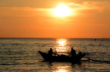 Wild beautiful beaches of Sri Lanka. Golden tropical sunset. Silhouette of  fishermen on the horizon.