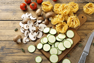 Obraz na płótnie Canvas vista dall'alto pasta italiana con verdure su tavolo di legno rustico
