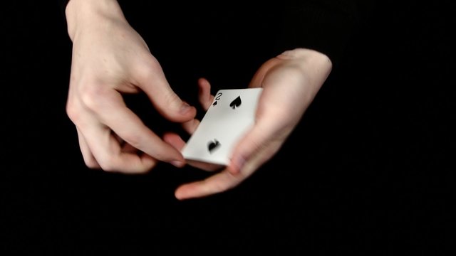 Playing cards being changing, on a black surface by magician