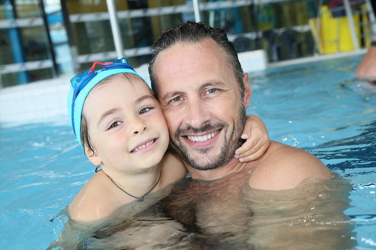 Portrait of man with cute little boy in swimming pool
