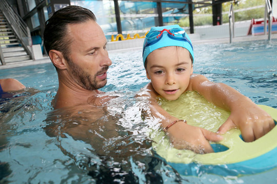 Boy child learning to swim with trainer