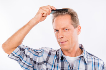 Handsome keen aged man combing his hair