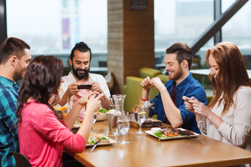 happy friends taking picture of food at restaurant