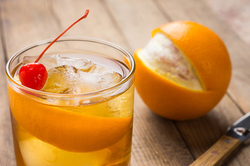 Old fashioned cocktail with cherry and orange peel