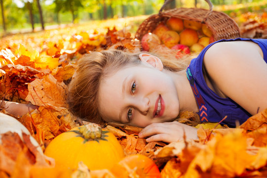 Portrait of girl on leaves with pumpkin and apples