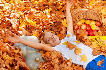 Smiling boy laying on the leaves with harvest