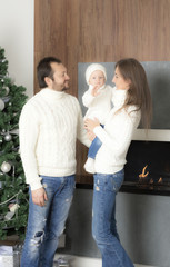 Family portrait near the Christmas tree. Family dressed in a white sweaters.